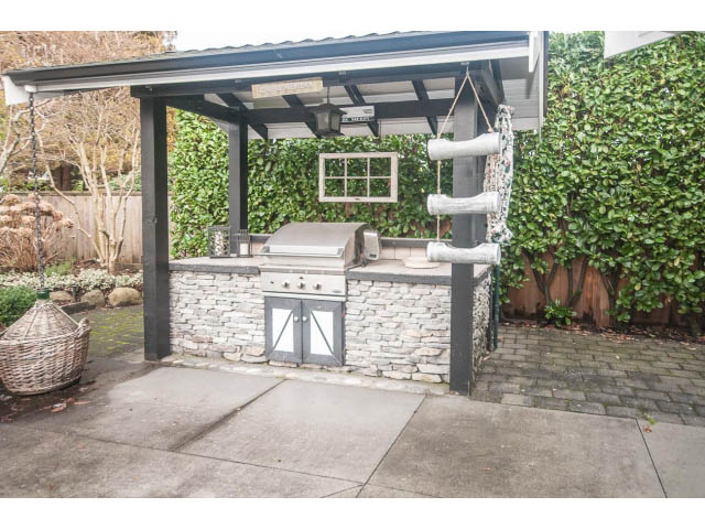 Outdoor patio with stone countertop and swing hanging from pergola. - 840 16th East St, North Vancouver