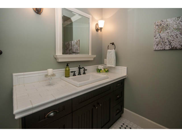 Bathroom with white countertop, dark cabinets, and a wall-mounted light fixture. - 840 16th East St, North Vancouver