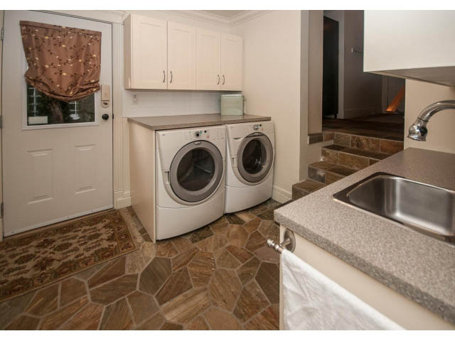 Bright laundry room with granite countertops and stone tile flooring. - 840 16th East St, North Vancouver