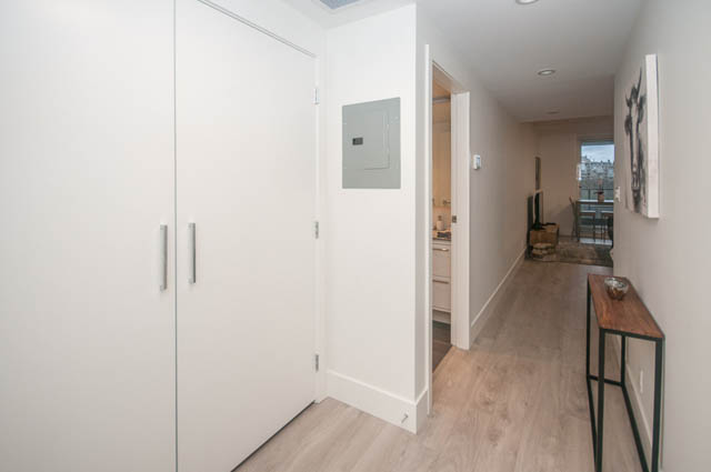 Bright hallway with white cabinets and hardwood floors, leading to a cozy living area with a city view. - 907 - 680 Seylynn Crescent, North Vancouver