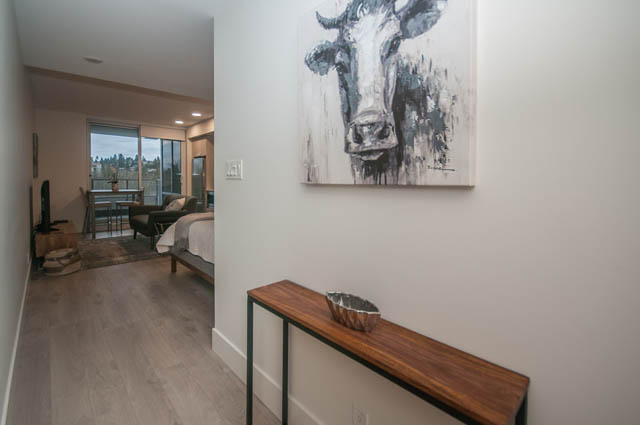 Bright living room with cow artwork and hardwood floors. - 907 - 680 Seylynn Crescent, North Vancouver