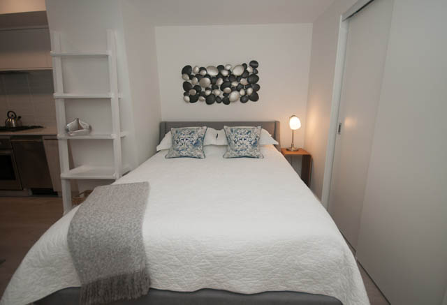 Bright bedroom with white bedding, blue and white pillows, and a modern art piece on the wall. - 907 - 680 Seylynn Crescent, North Vancouver
