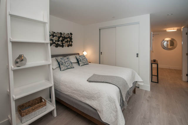 Bright bedroom with white walls, modern decor, and a sliding closet door. - 907 - 680 Seylynn Crescent, North Vancouver