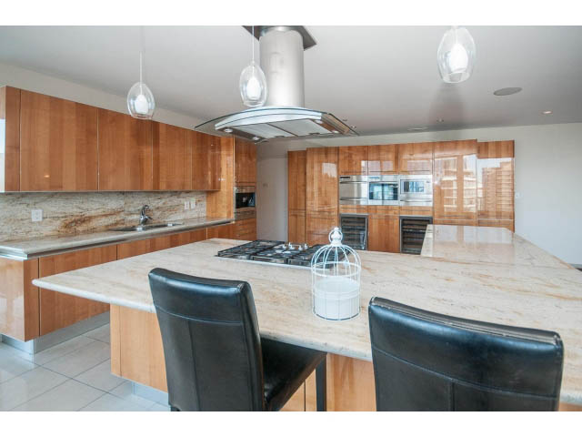 Bright kitchen with marble countertops and modern pendant lights, showcasing a spacious and stylish design.