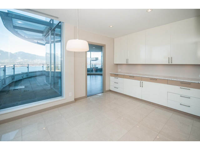 Bright kitchen with white cabinets, light wood countertops, and a city view through large windows. - 2200 - 1169 W Cordova St, Vancouver Downtown