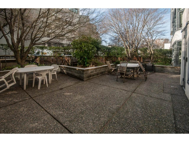 Furnished patio with outdoor tables and chairs, surrounded by trees and buildings. - 108 - 456 Moberly Rd, Vancouver West Side