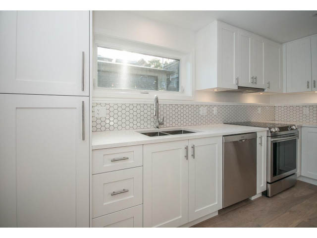 Bright kitchen with white cabinets, hexagonal tile backsplash, and stainless steel appliances. - 4216 W 10th Ave, Vancouver West Side