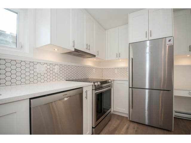 Bright kitchen with white cabinets, hexagonal tile backsplash, stainless steel appliances, and hardwood floors. - 4216 W 10th Ave, Vancouver West Side