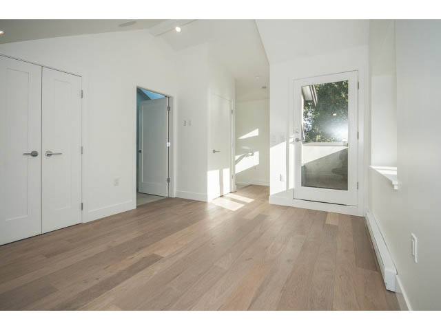 Bright entryway with hardwood floors and white walls, leading to a hallway with a door and window view. - 4216 W 10th Ave, Vancouver West Side