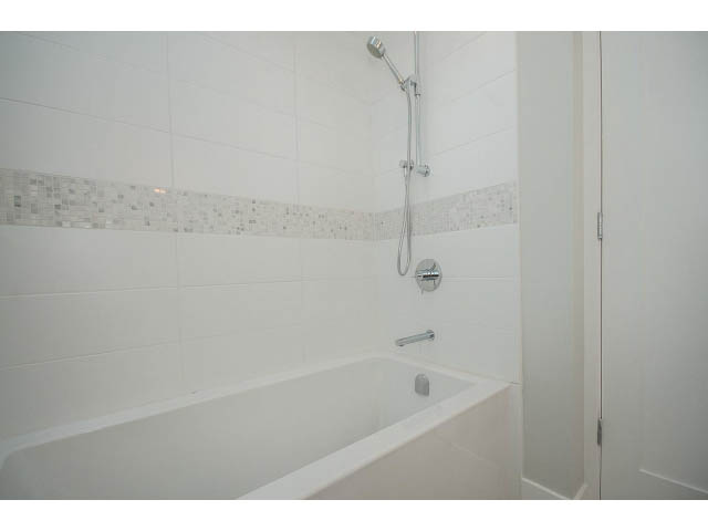 Bright bathroom with white bathtub and mosaic tile accent. - 4216 W 10th Ave, Vancouver West Side