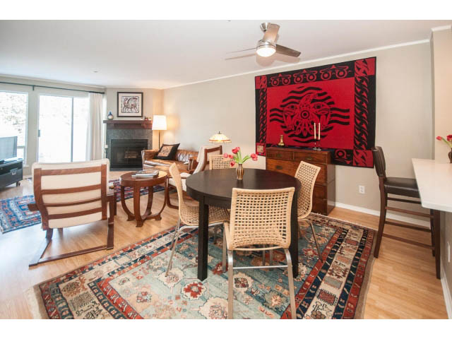 Furnished living room with hardwood floors, patterned rugs, and a large red tapestry. - 301 - 2288 Laurel St, Vancouver West Side