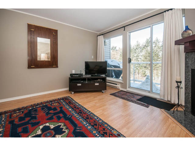 Bright living room with hardwood floors, large windows, and a colorful rug. - 301 - 2288 Laurel St, Vancouver West Side