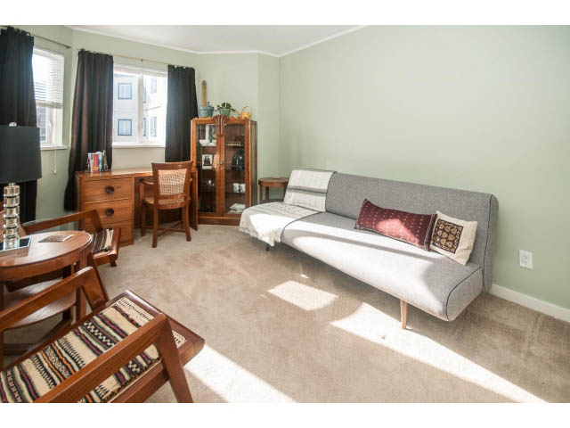 Furnished living room with light green walls, gray sofa, wooden furniture, and natural light from window. - 301 - 2288 Laurel St, Vancouver West Side