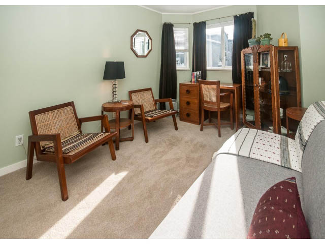 Bright living room with patterned armchairs and a cozy rug, natural light from windows. - 301 - 2288 Laurel St, Vancouver West Side