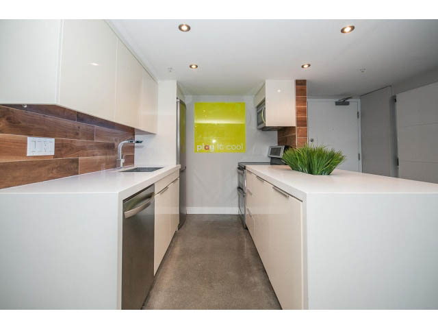 Bright kitchen with white countertops and wooden backsplash, modern design. - 307 - 1238 Seymour Street, Vancouver Downtown