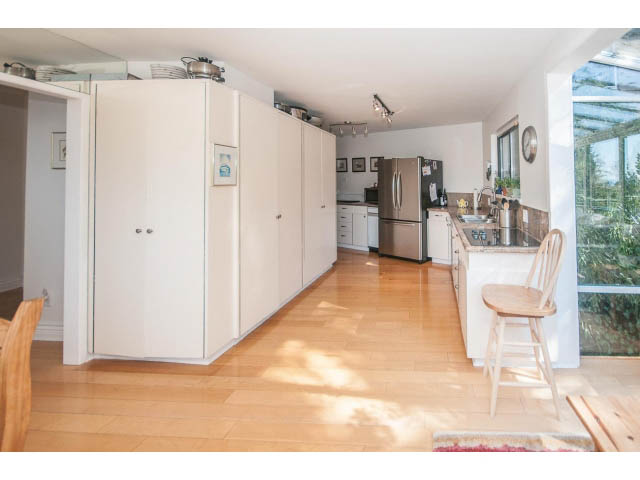 Bright kitchen with hardwood floors and modern appliances, open to a dining area. - 3855 Bayridge Ave, West Vancouver