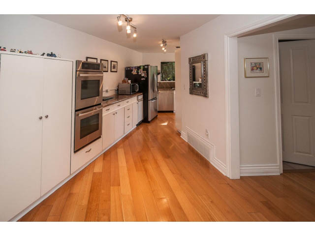 Bright kitchen with white cabinets, stainless steel appliances, and hardwood floors. - 3855 Bayridge Ave, West Vancouver