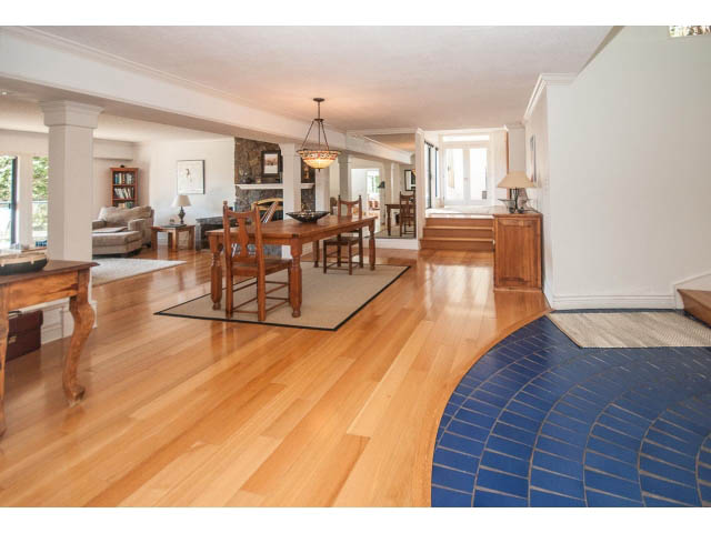 Bright living room with hardwood floors, large windows, and a cozy fireplace. - 3855 Bayridge Ave, West Vancouver