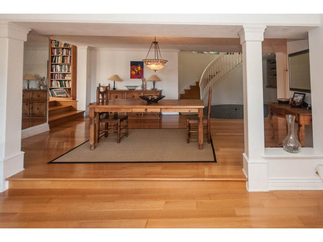 Open-concept living area with hardwood floors, a spiral staircase, and a large wooden dining table. - 3855 Bayridge Ave, West Vancouver