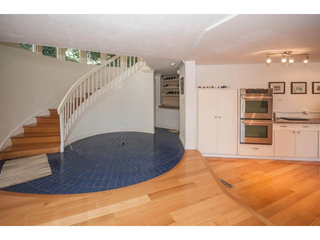 Bright kitchen with hardwood floors and blue tiled backsplash, featuring a modern oven and white cabinetry. - 3855 Bayridge Ave, West Vancouver