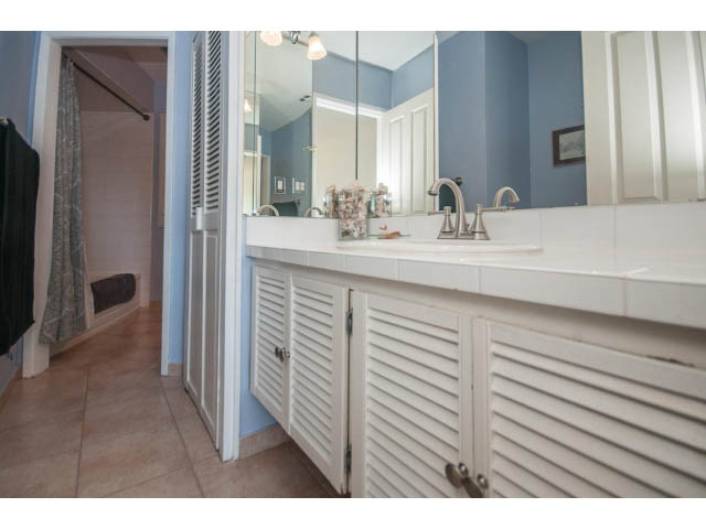 Bright bathroom with white louvered cabinets and double sink, blue walls. - 3855 Bayridge Ave, West Vancouver