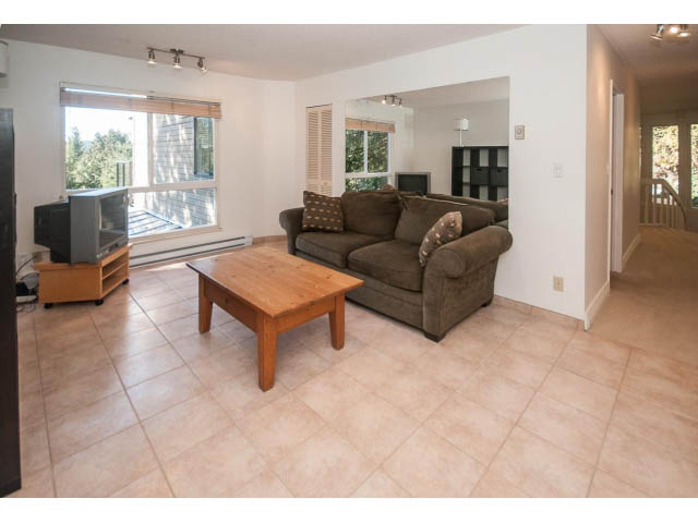 Spacious living room with tiled floors, brown furniture, and a view of the outdoors. - 3855 Bayridge Ave, West Vancouver