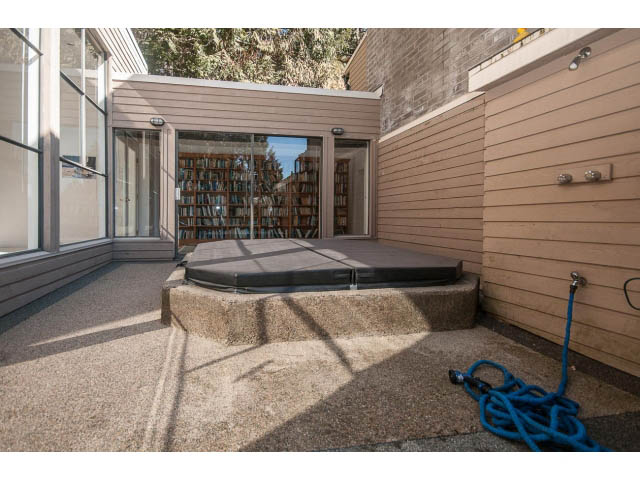 Furnished patio with wooden siding and a hose, leading to a glass door. - 3855 Bayridge Ave, West Vancouver