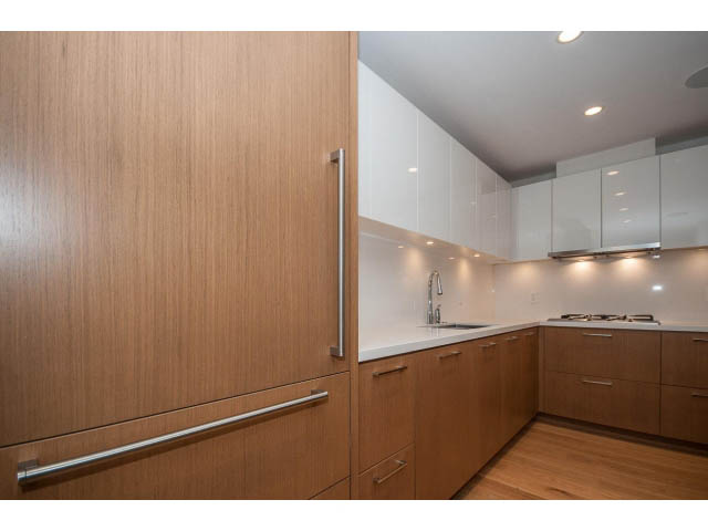 Bright kitchen with modern white cabinets, wooden accents, and stainless steel appliances. - 204 - 788 Arthur Erickson Pl, West Vancouver