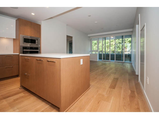 Bright kitchen with wooden cabinets, hardwood floors, and a city view. - 204 - 788 Arthur Erickson Pl, West Vancouver