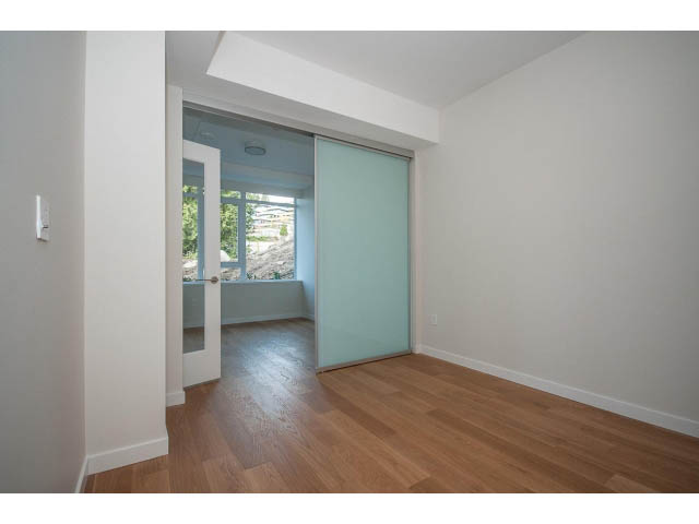 Bright living room with hardwood floors and sliding glass doors leading to a balcony. - 204 - 788 Arthur Erickson Pl, West Vancouver