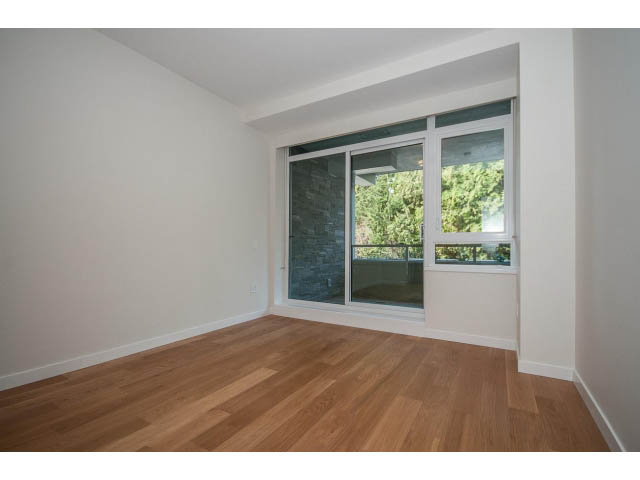 Bright living room with hardwood floors and large windows offering a city view. - 204 - 788 Arthur Erickson Pl, West Vancouver