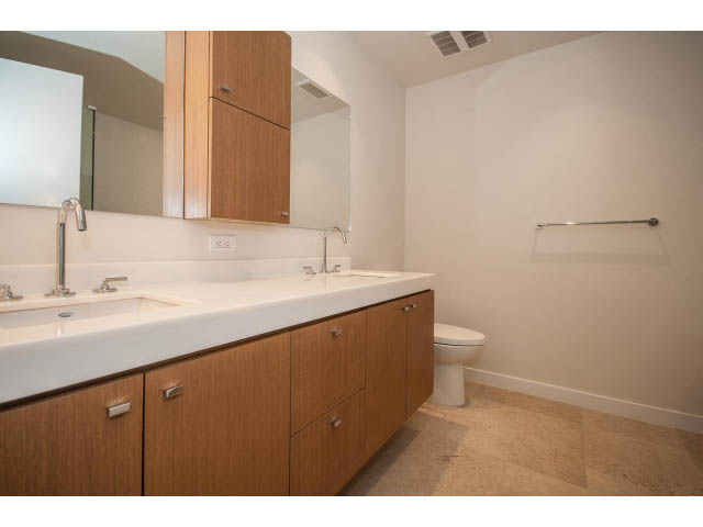 Modern bathroom with white countertops and wooden cabinets. - 204 - 788 Arthur Erickson Pl, West Vancouver