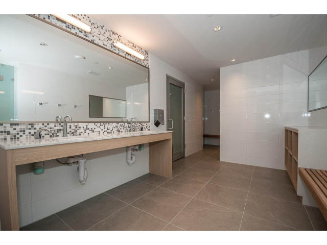 Furnished bathroom with large mirror, modern sink, and tiled walls. - 204 - 788 Arthur Erickson Pl, West Vancouver