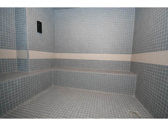 Spacious steam room with tiled walls and benches. - 204 - 788 Arthur Erickson Pl, West Vancouver
