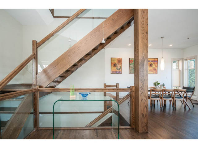 Open-concept living area with wooden stairs, glass railings, and hardwood floors. - 3131 Collingwood St, Vancouver West Side