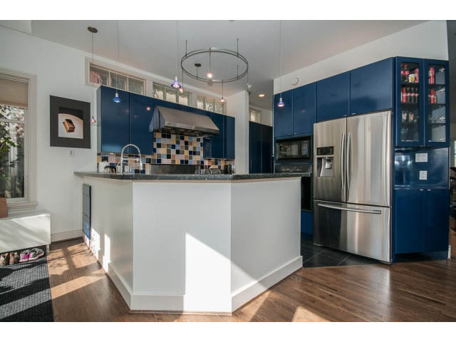 Bright kitchen with blue cabinets, stainless steel appliances, and hardwood floors. - 3131 Collingwood St, Vancouver West Side