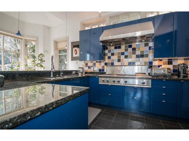 Bright kitchen with blue cabinets, granite countertops, and a colorful tiled backsplash. - 3131 Collingwood St, Vancouver West Side