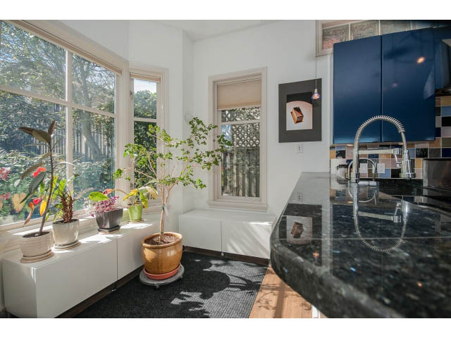 Bright kitchen with black granite countertops and a large window, showcasing a city view. - 3131 Collingwood St, Vancouver West Side