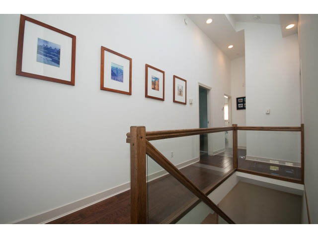 Staircase with wooden railings and framed artwork on white walls. - 3131 Collingwood St, Vancouver West Side