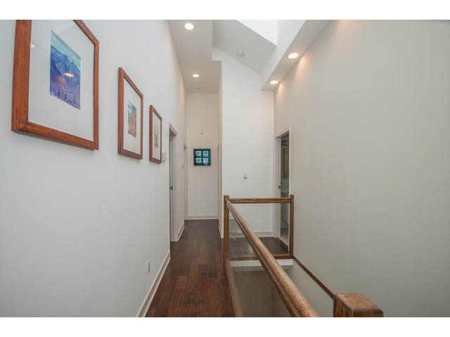 Staircase leading to upper floor with wooden handrails and framed artwork on the wall. - 3131 Collingwood St, Vancouver West Side