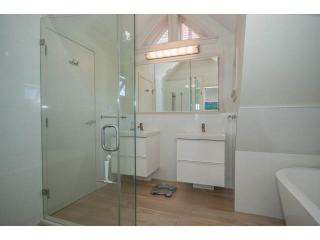 Bright bathroom with white fixtures, glass shower, and wooden floors. - 3131 Collingwood St, Vancouver West Side