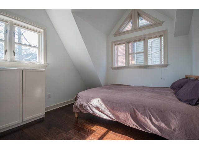Bright attic bedroom with slanted ceiling, hardwood floors, and purple bedding. - 3131 Collingwood St, Vancouver West Side