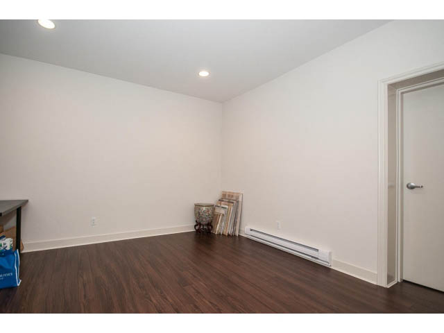 Bright den with hardwood floors and white walls, featuring a small table and a door leading to another room.