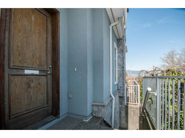 Furnished entryway with wooden door and stone steps leading to a balcony with city view. - 3131 Collingwood St, Vancouver West Side