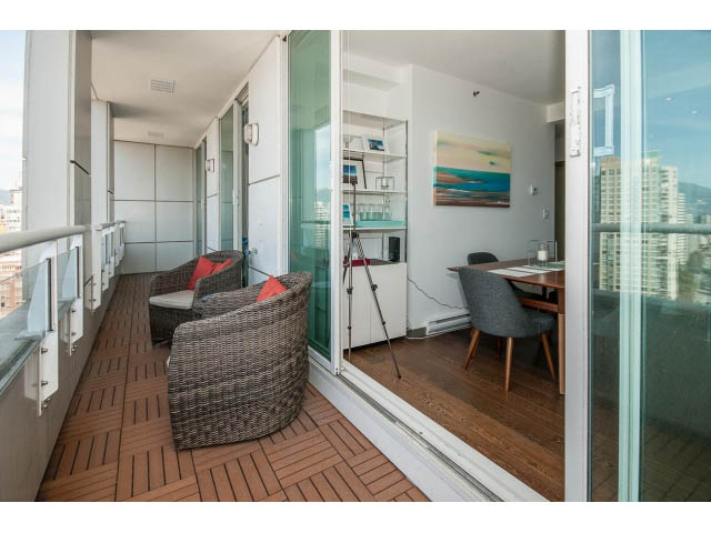 Furnished balcony with wooden flooring, city view, and wicker furniture. - 2404 - 1500 Hornby St, Vancouver Downtown