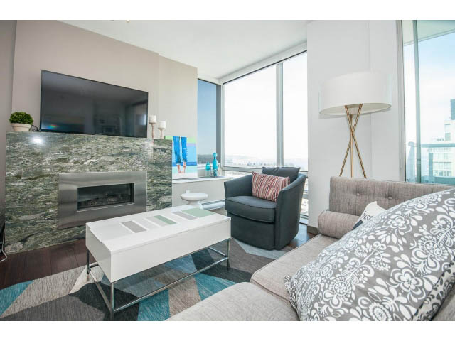 Spacious living room with marble fireplace, modern furniture, and city view. - 2404 - 1500 Hornby St, Vancouver Downtown