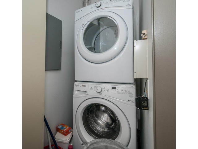 Bright laundry room with stacked washer and dryer, clean and organized. - 2404 - 1500 Hornby St, Vancouver Downtown