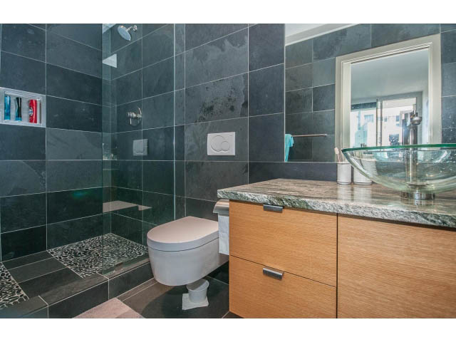 Modern bathroom with glass bowl sink and dark tiled walls. - 2404 - 1500 Hornby St, Vancouver Downtown