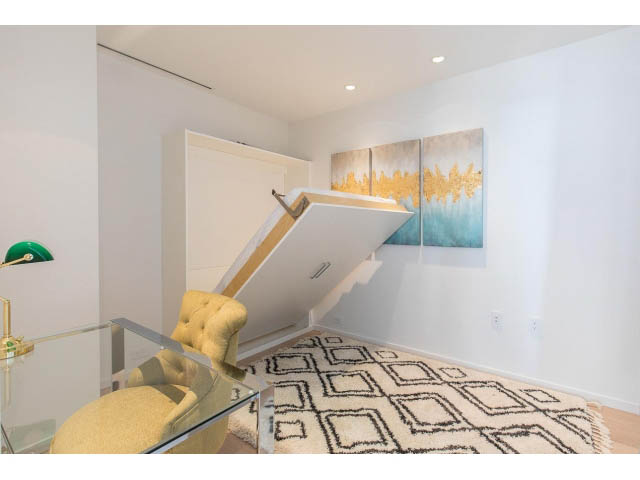 Furnished living room with modern artwork, glass coffee table, and geometric rug. - 1901 - 1171 Jervis St, Vancouver Downtown