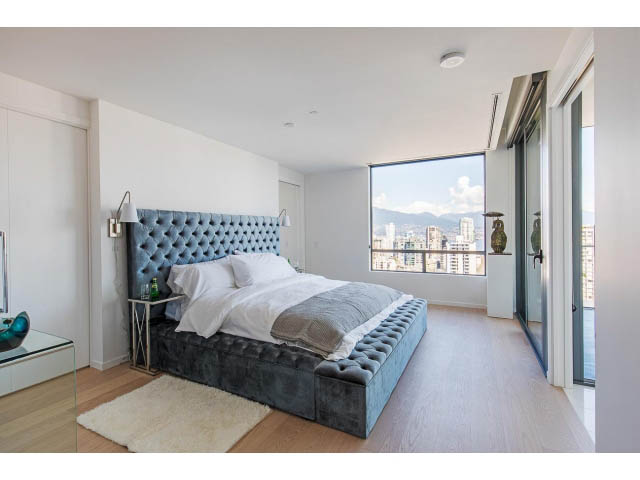 Furnished penthouse bedroom with hardwood floors, city view, and tufted headboard. - 1901 - 1171 Jervis St, Vancouver Downtown